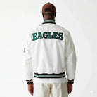 White Eagles varsity jacket with green lettering, striped cuffs and collar, worn with brown cap