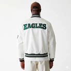 White Eagles varsity jacket with green lettering, striped cuffs and collar, worn by model