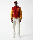 Red and gold varsity jacket with embroidered M, paired with white pants and sneakers