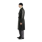 Man wearing black leather trench coat with belt, beanie, and gray trousers, side view
