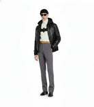Man wearing black leather jacket, Batman graphic turtleneck, gray trousers, and sunglasses