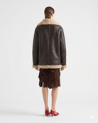 Brown leather jacket with shearling collar and cuffs, paired with ruffled skirt and red heels