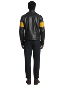 Black leather jacket with yellow striped sleeves, worn with dark pants and brown shoes