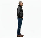 Man in black leather bomber jacket with shearling collar, blue jeans, and brown boots, side profile