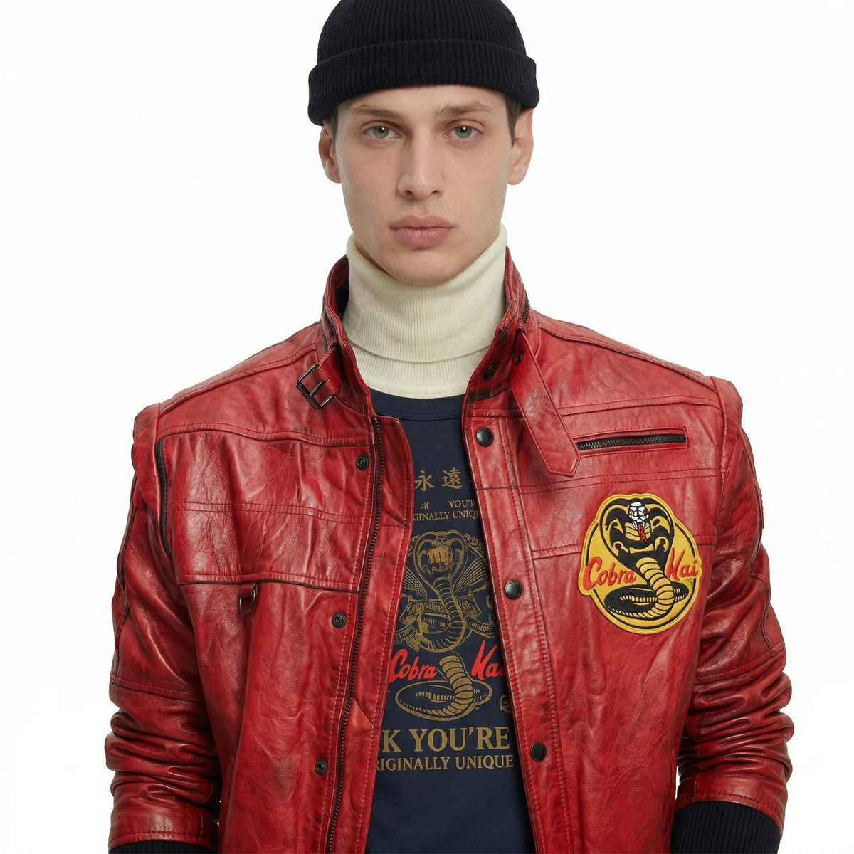 Red leather jacket with Cobra Kai patch, worn over graphic tee and turtleneck, styled with black beanie