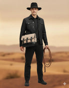 Man in black cowboy hat and jacket carrying beige satchel bag, holding rope in desert setting