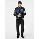 Navy blue varsity jacket with star logo and striped sleeves, paired with black jeans