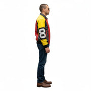 Man wearing red yellow black racing jacket with number 8, blue jeans, brown shoes, side view