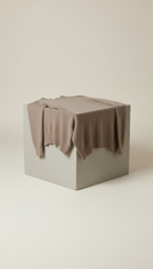 Beige knit sweater draped over concrete block, minimalist style