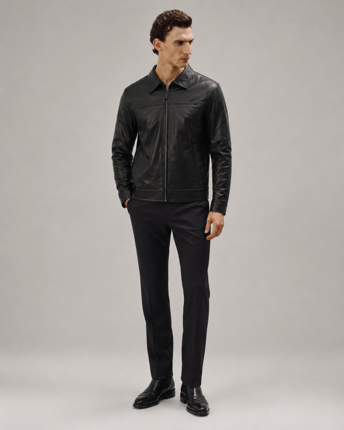 Men's black leather jacket with zipper, paired with slim-fit trousers and dress shoes
